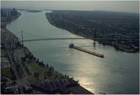 A freighter passes underneath the Ambassador bridge. Strait City Trading Co is located in Detroit, a center for international trade.