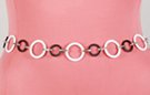 black and white furrowed circle chain belt; nickel-sized black circles alternate with larger white, all joined by embossed silver oval links
