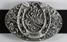 oval western belt buckle with horseshoe on foliage background