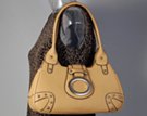 creamy tan teardrop frame handbag with saddle flap, ornamental oval and corner studs