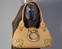 creamy tan teardrop frame handbag with saddle flap, ornamental oval and corner studs